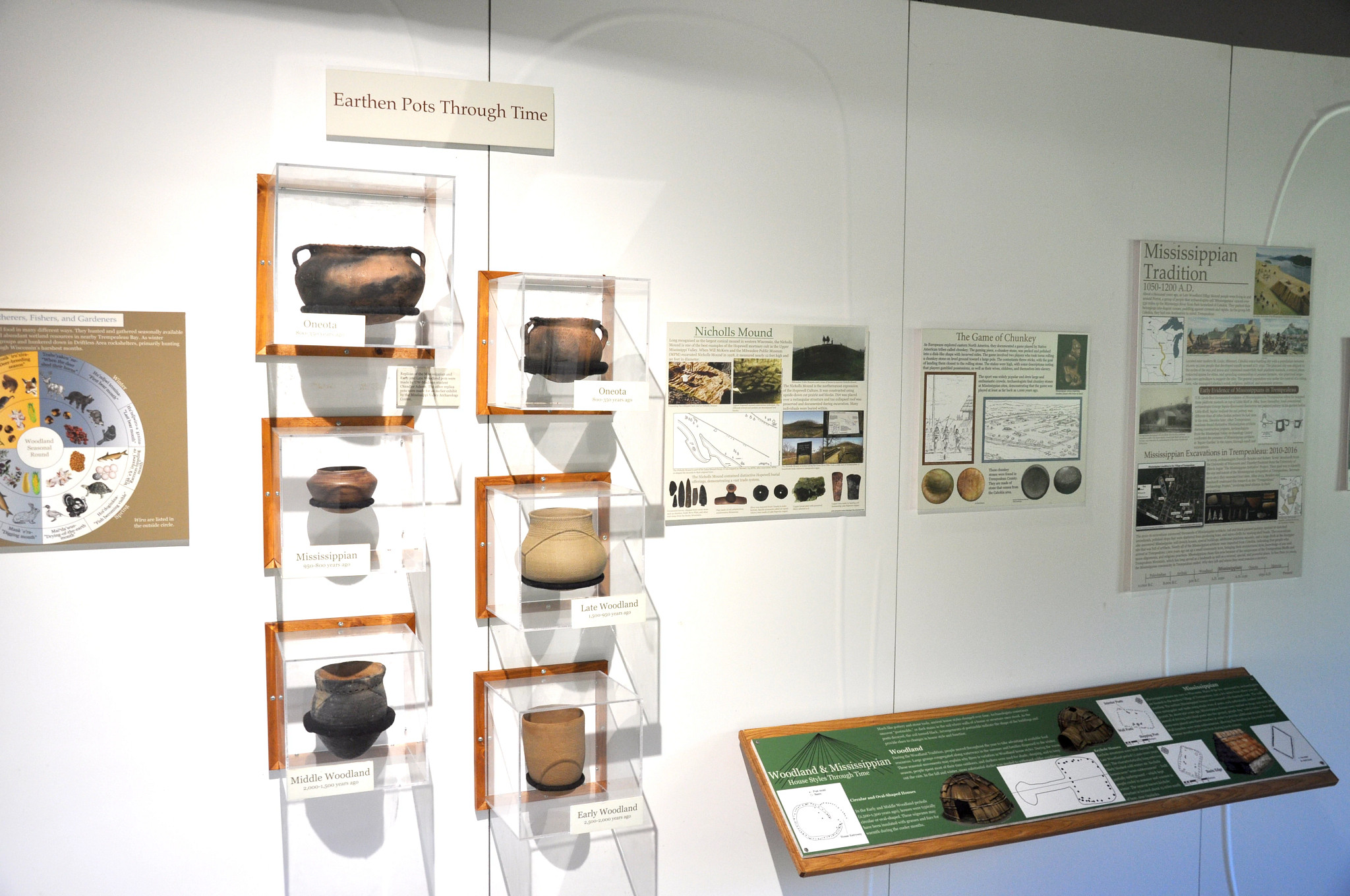 Native American pots are displayed in cases on the wall by age.