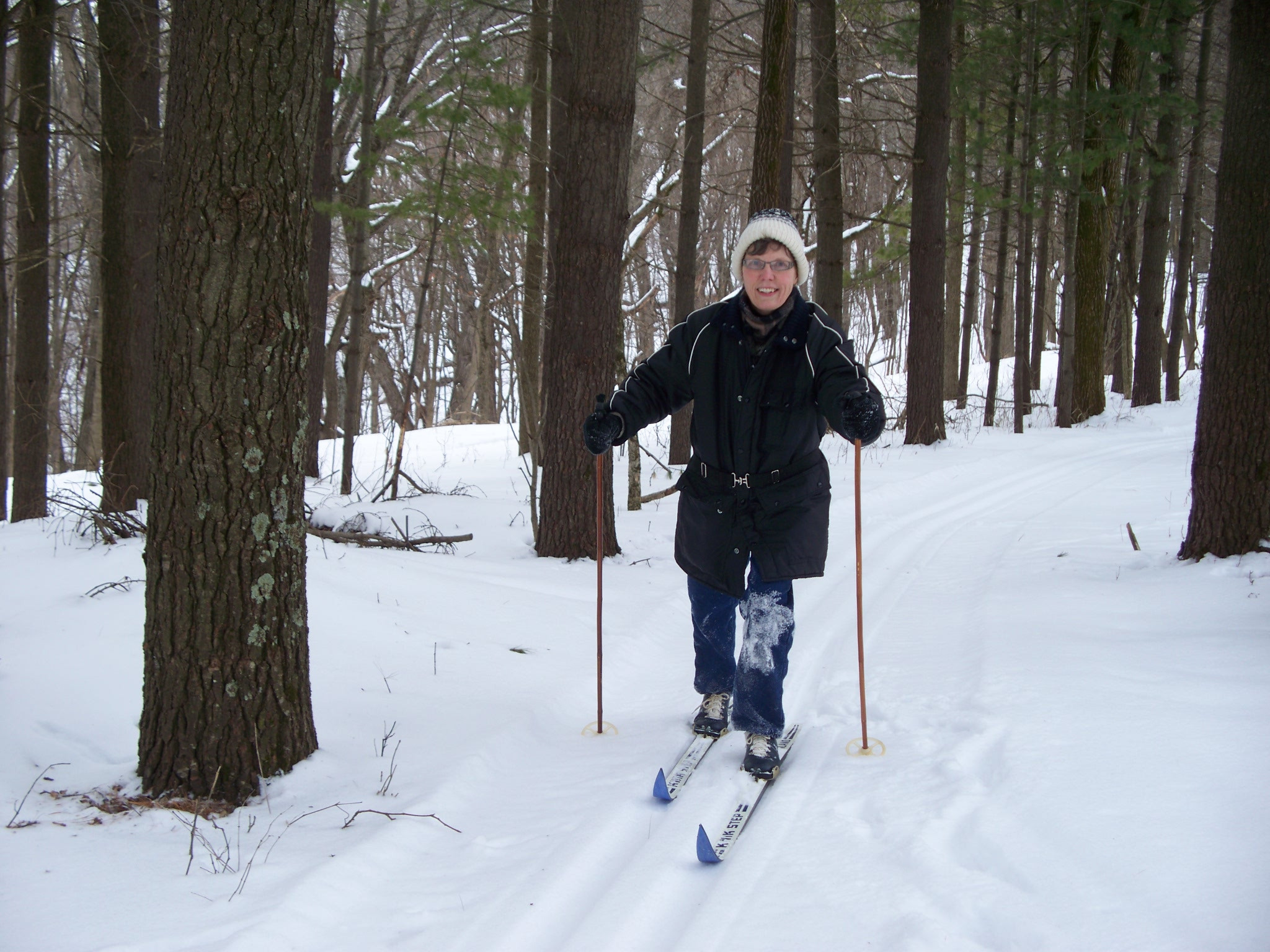 Woman skis through the woods with a smile.