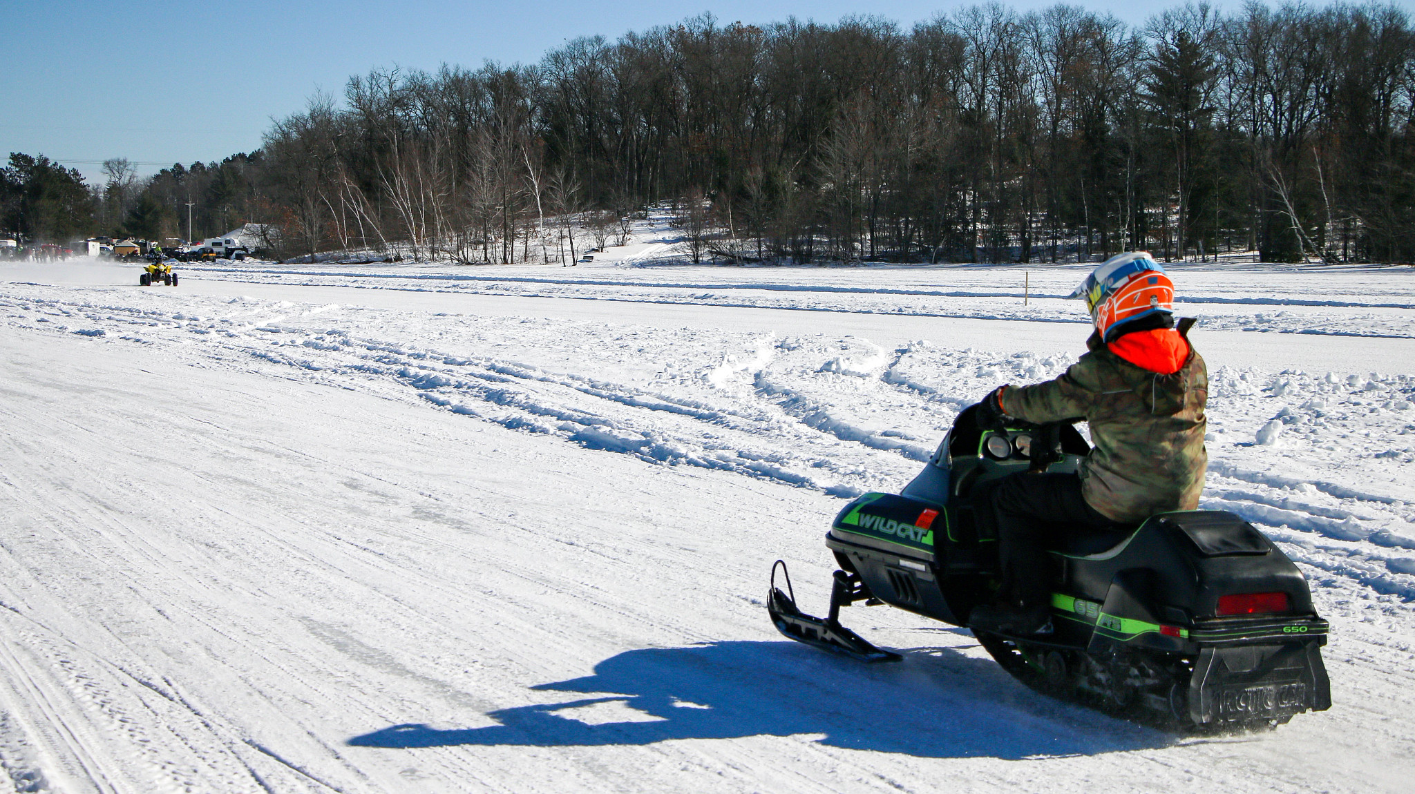 A snowmobiler drives on a path, cruising away from the camera. 