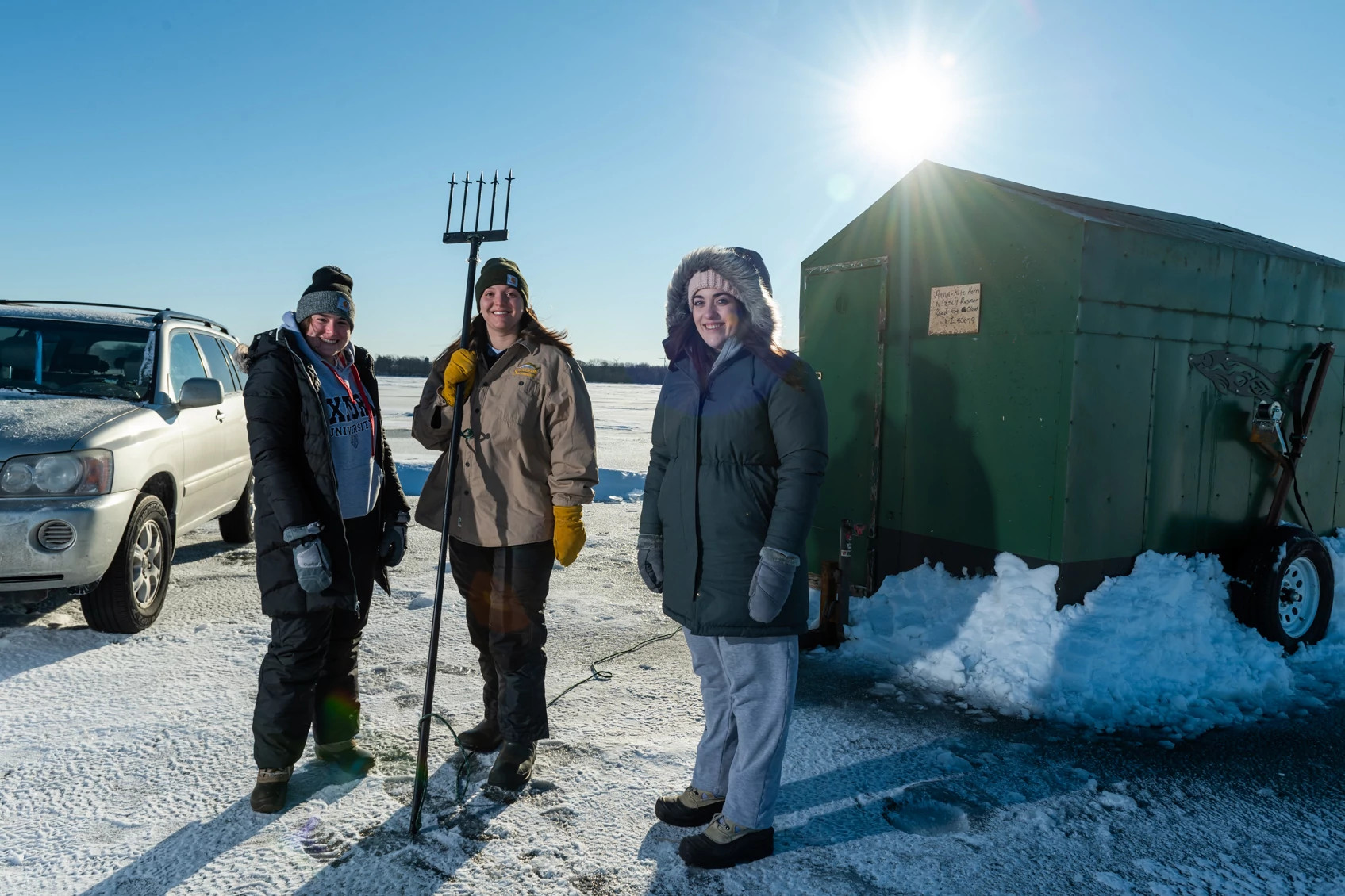 three women getting ready to spear sturgeon on a frozen lake