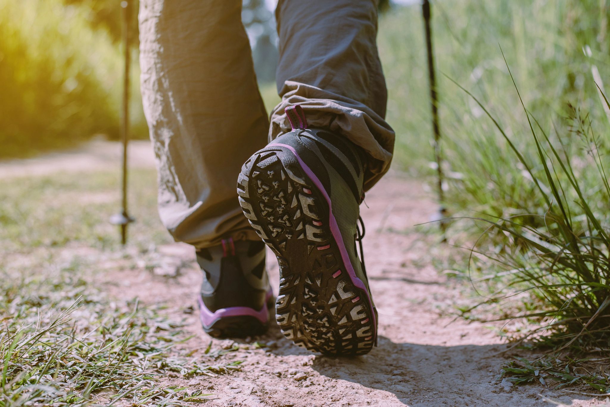 A close-up image of a person's shoes while hiking a trail.