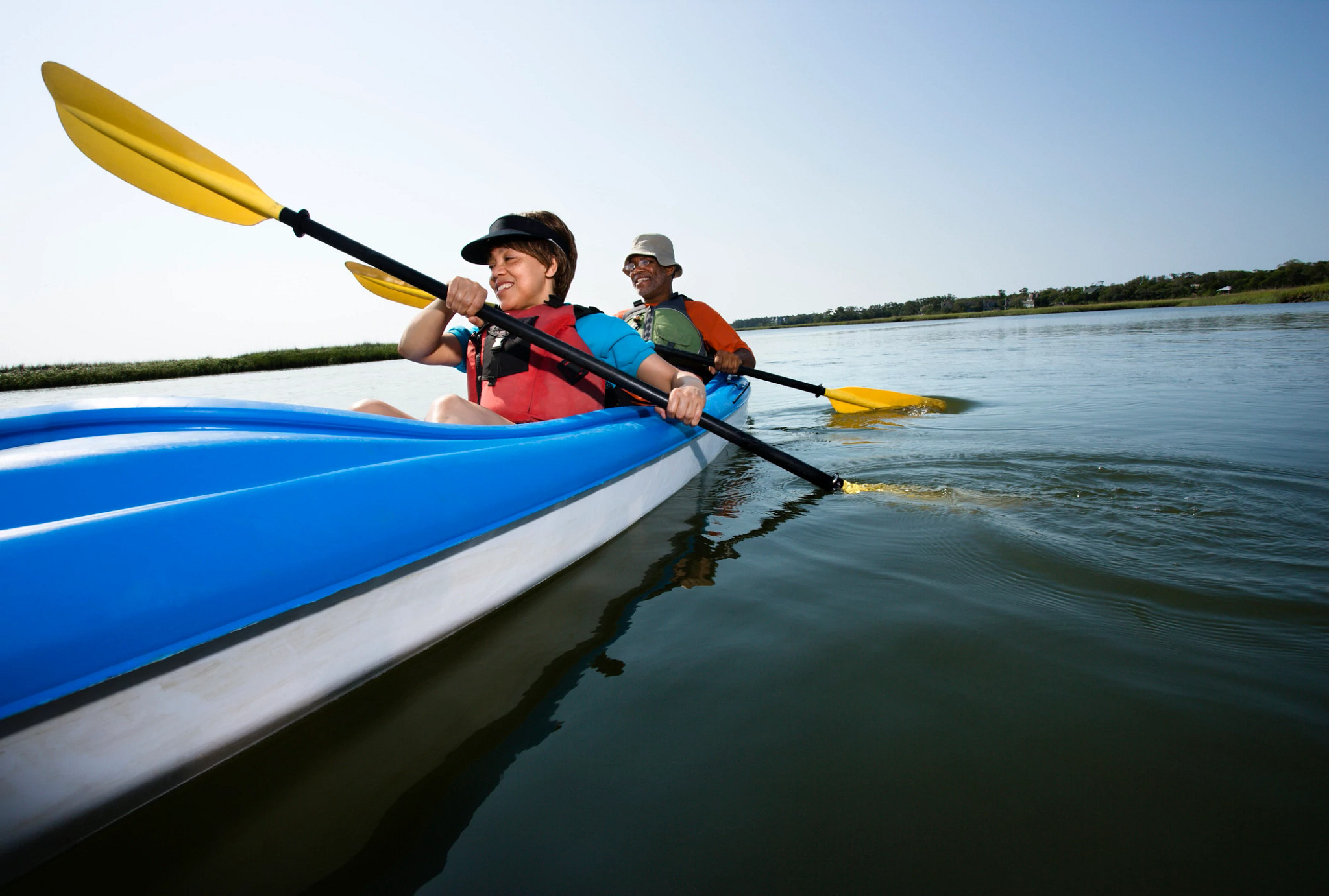 Low angle of African American middle-aged man and woman paddling kayak.
