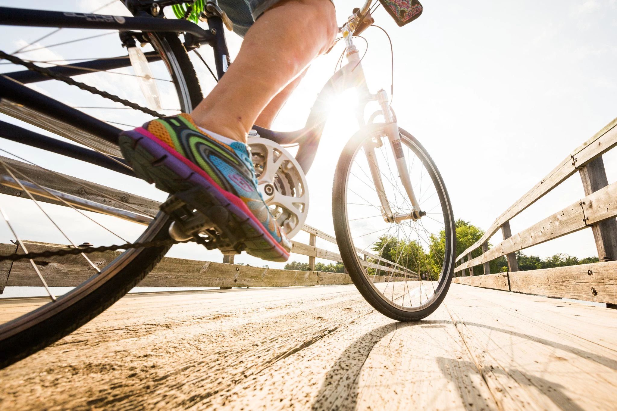 A close up of a biker's pedal. The biker is on a pier.