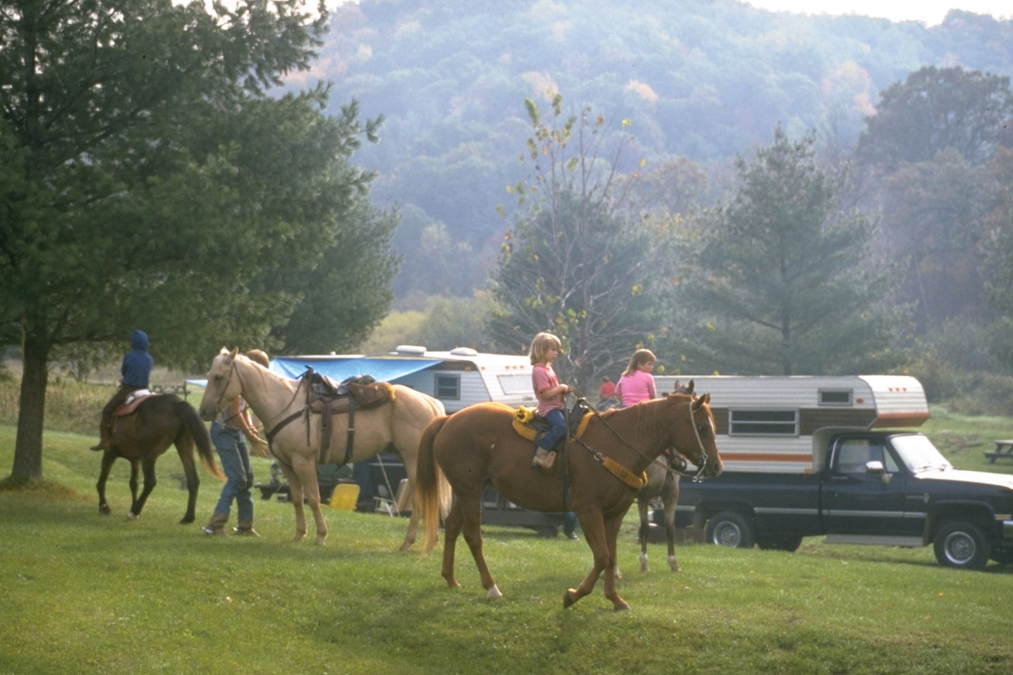 Riders on horses wait near a paddock with a view of wildcat mountain.