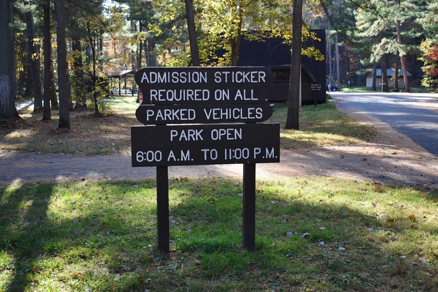 a wooden sign at a Wisconsin State Park that says "Admission sticker required on all parked vehicles. Park open 6 a.m. - 11 p.m."