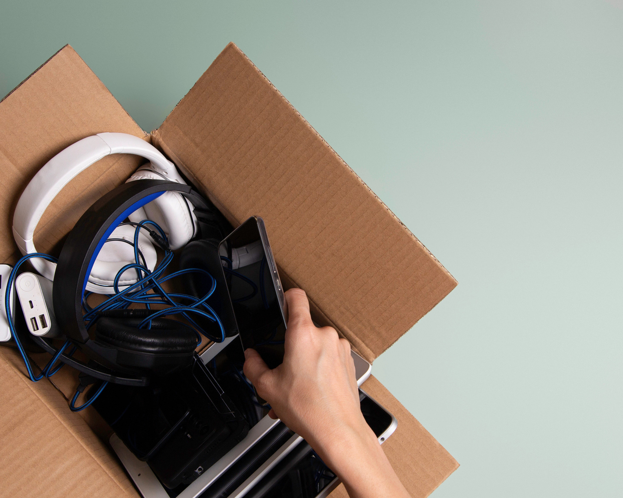 Electronics in a box to be recycled, including headphones and a cellphone. 