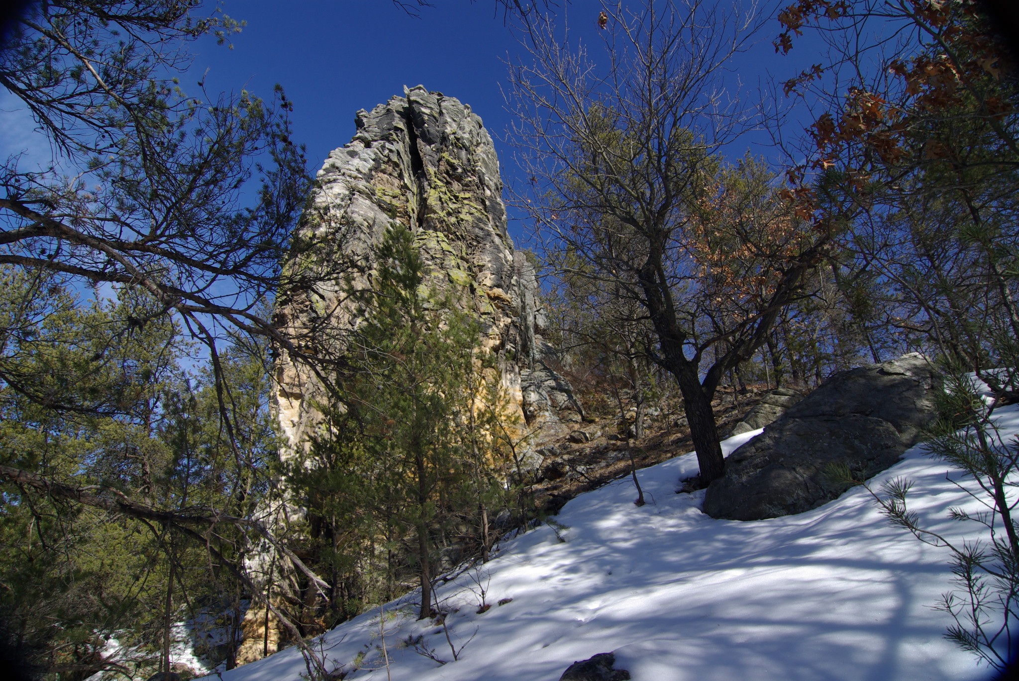 A steep hill in a forest with snow on the ground and huge stone formations throughout.
