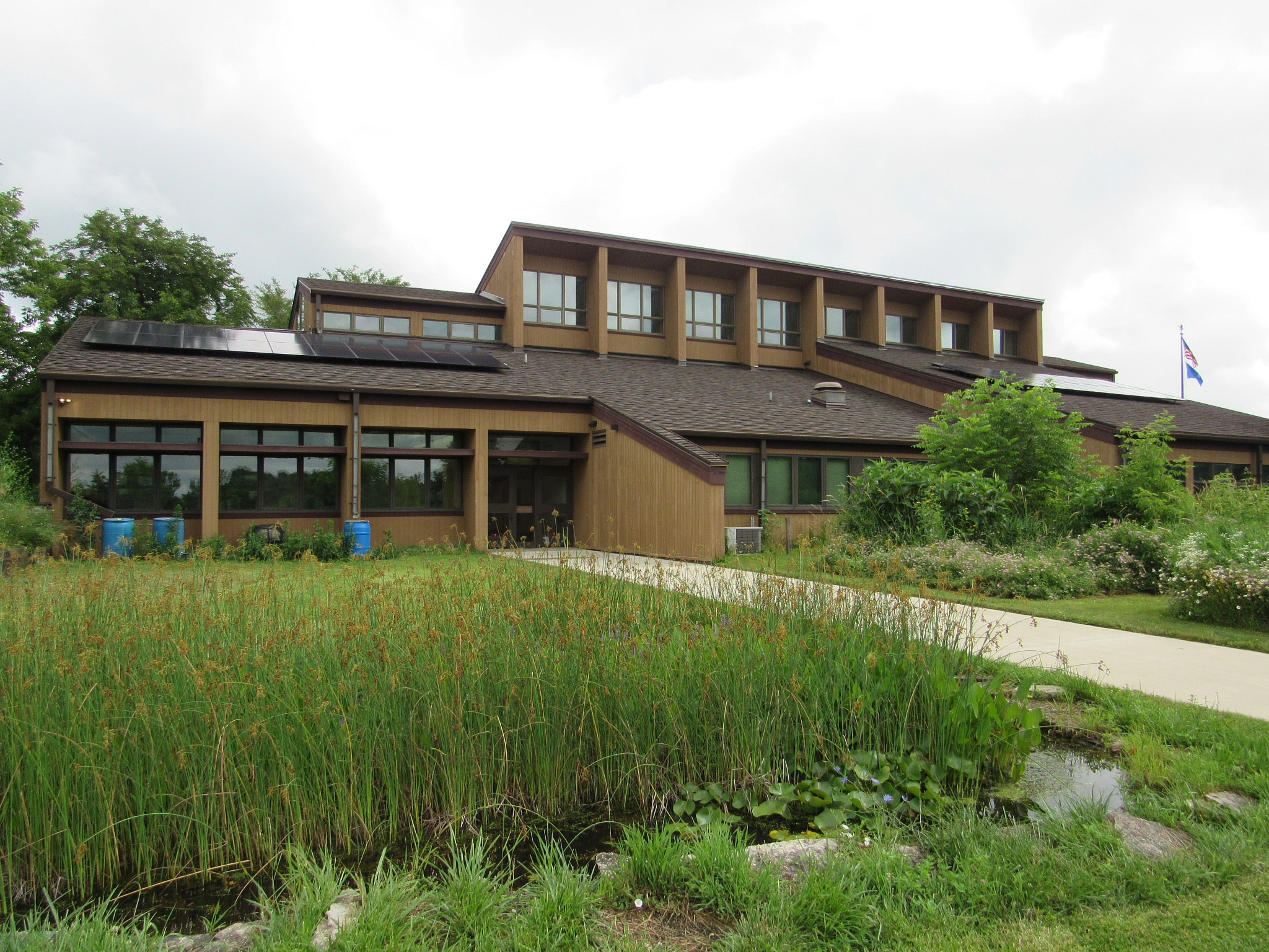 Exterior of the Havenwoods nature center with lots of windows and a pond in front.