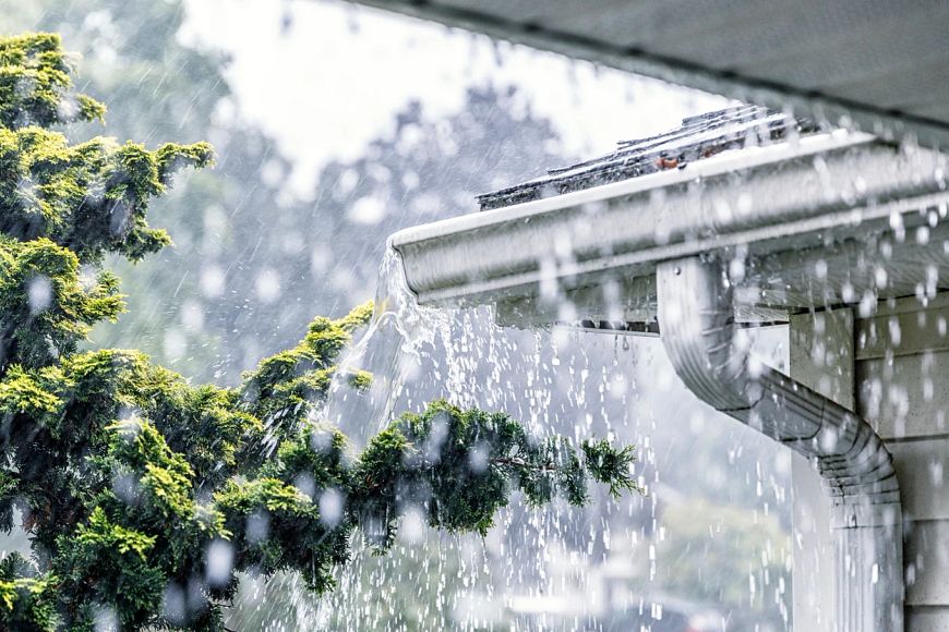 Drenching downpour rain storm water is overflowing off the tile shingle roof 