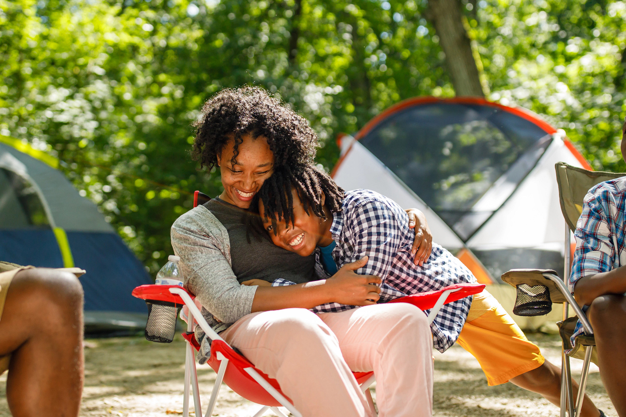 a mother and son embrace while sitting on camping chairs at a campsite at kegonsa state park