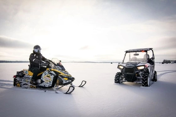 two Wisconsin DNR conservation wardens on a snowmobile and in a UTV on a frozen lake