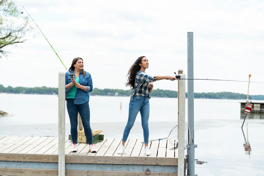two women fishing on a lake pier