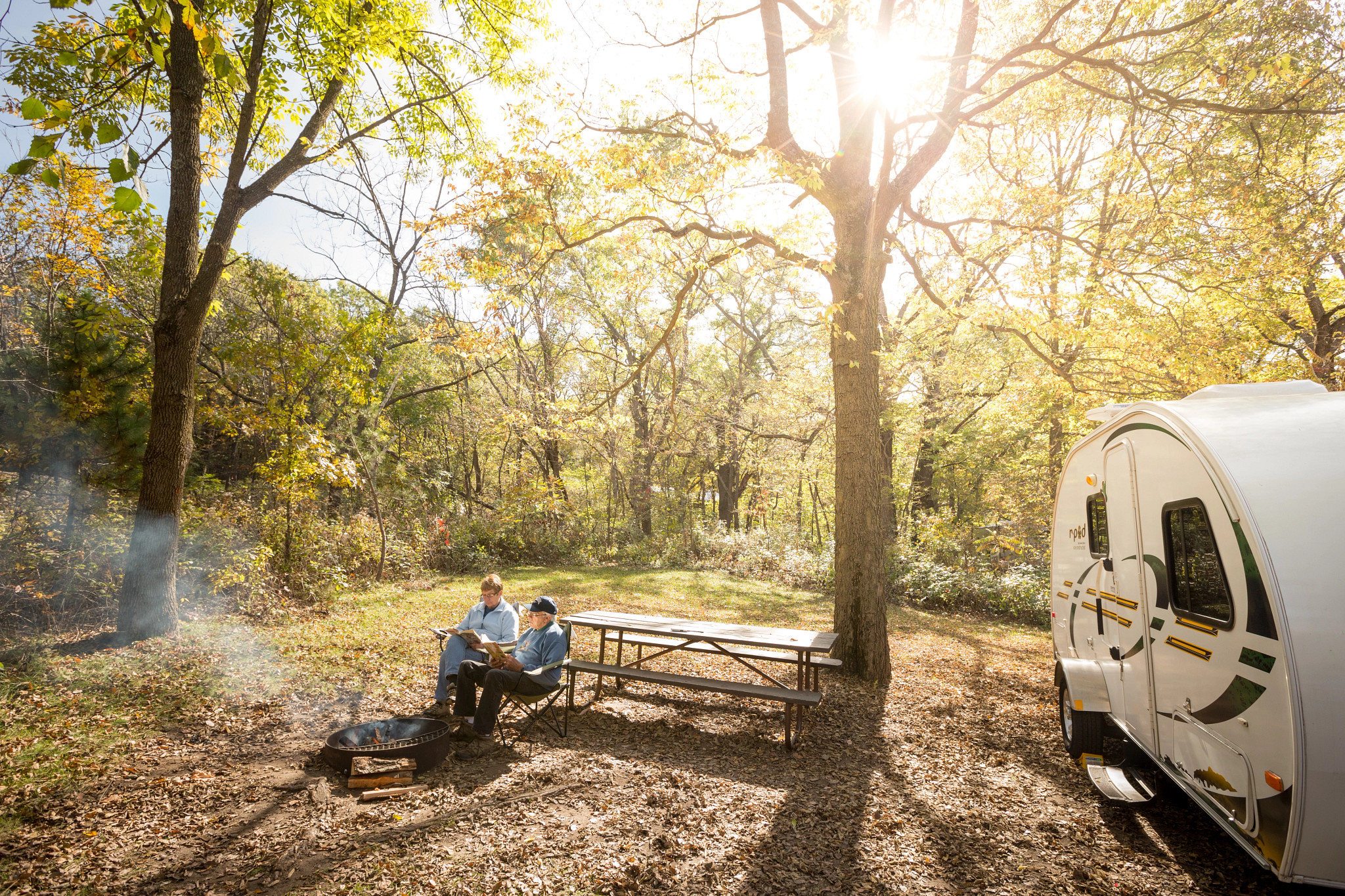 a couple sitting around the campfire at Perrot State Park with a camper also at the campsite