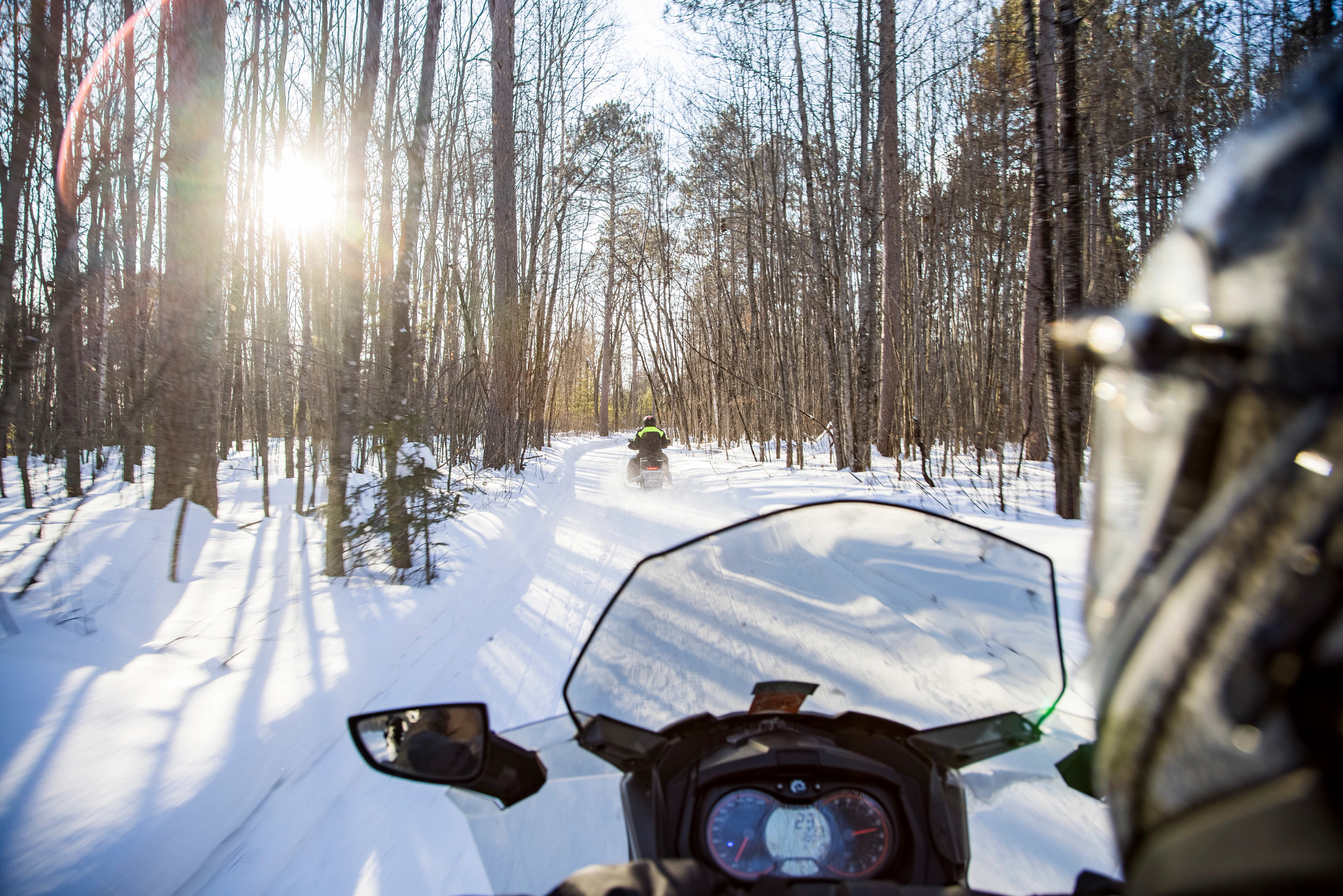 friends riding snowmobiles through snowy forest of saint germain