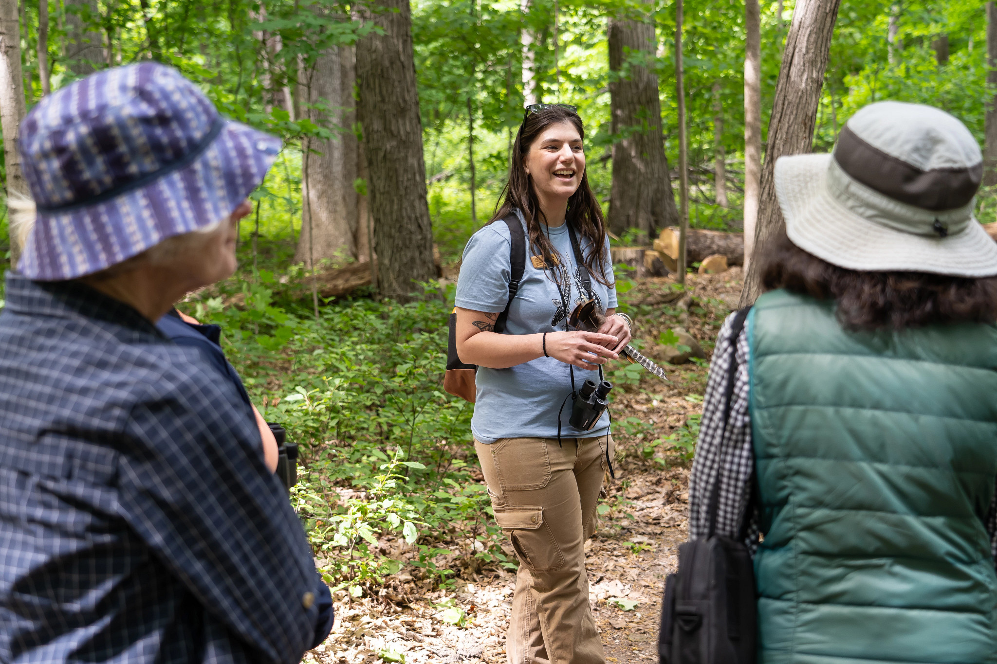A person speaks to two people in a forest.