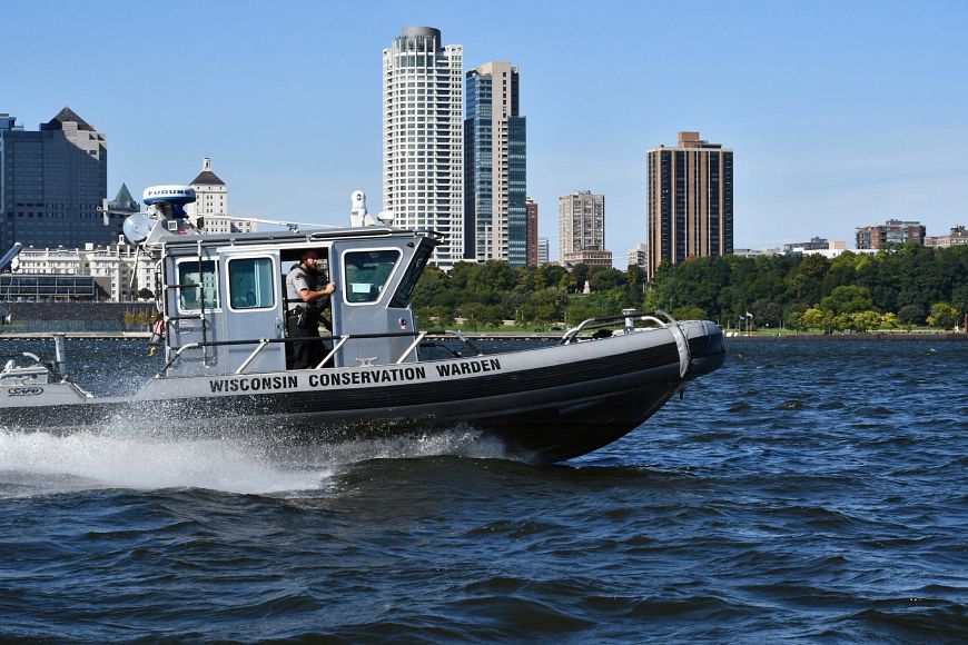 DNR Conservation Warden patrolling Lake Michigan on a boat near coastline