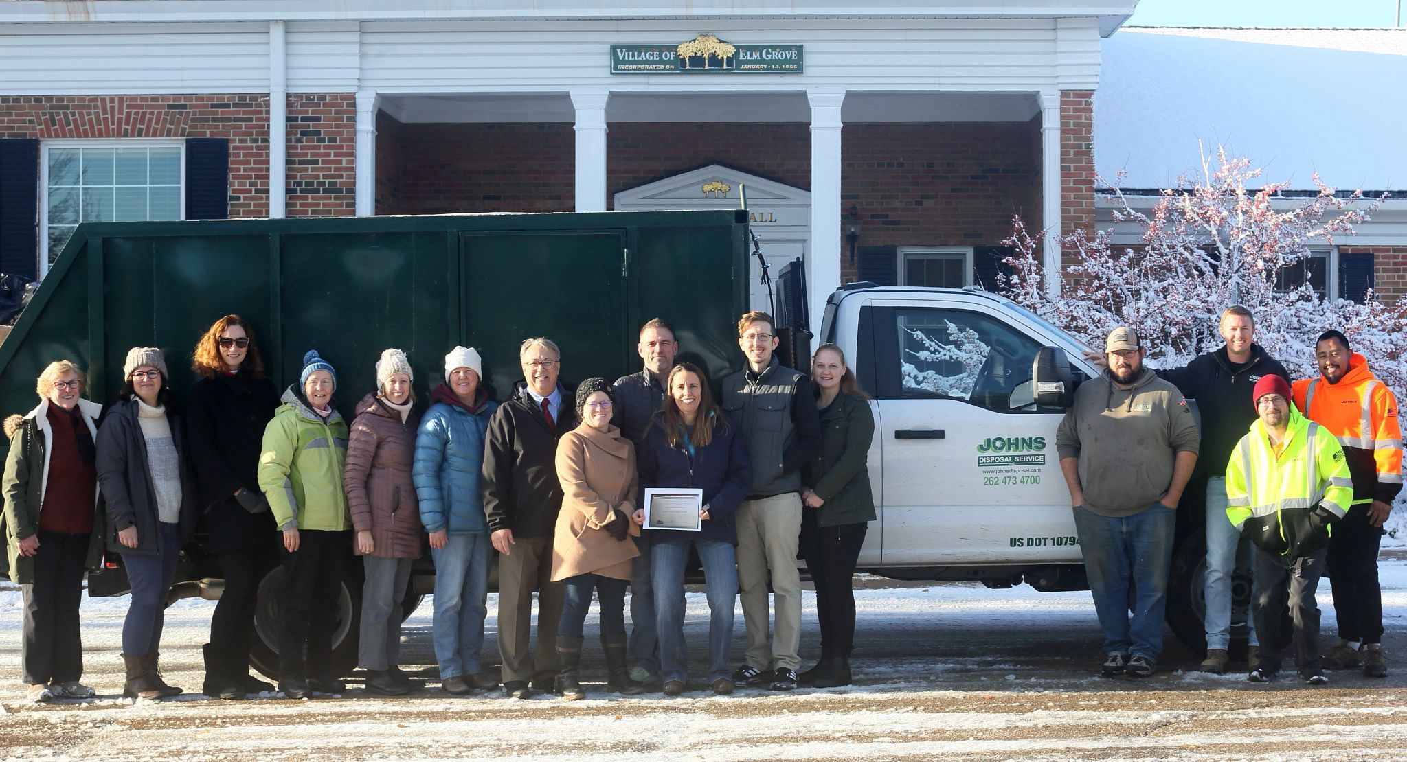 The Elm Grove Green Team poses in front of a haul-away truck with the group's 2023 Wisconsin Recycling Excellence Award certificate from the DNR.