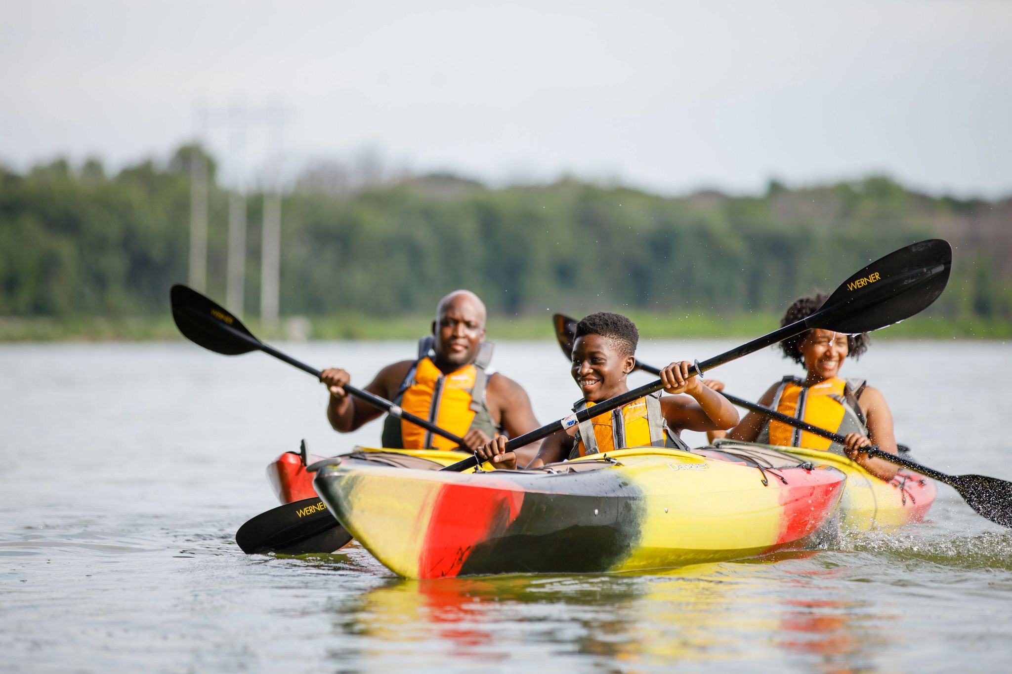 A family of three kayaks while wearing life jackets on Lake Kegonsa.