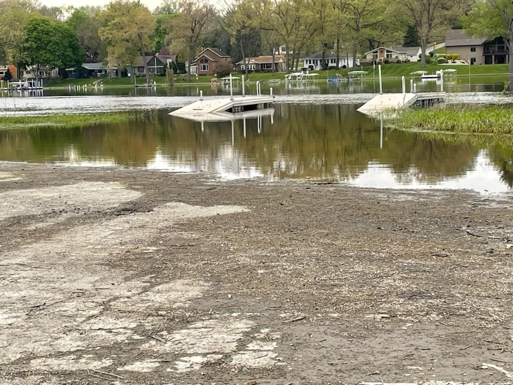 A boat launch along a river. Some water is pooled in front of the launch, showing signs of recent flooding.