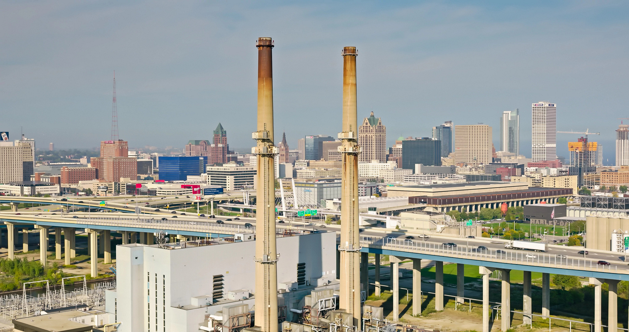 Aerial shot of downtown Milwaukee, Wisconsin on a hazy afternoon in Fall, looking past power plant chimneys and the Marquette Interchange