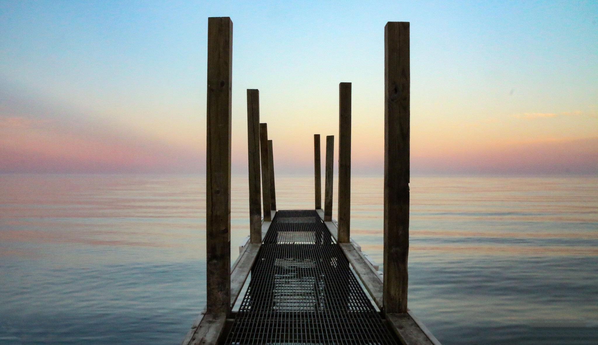 Photo of a dock stretching into a water body at dusk. The image, titled 