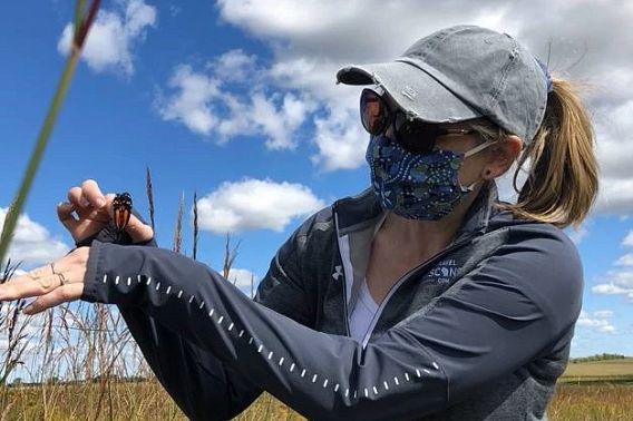 Woman standing in a prairie with a butterfly on her arm