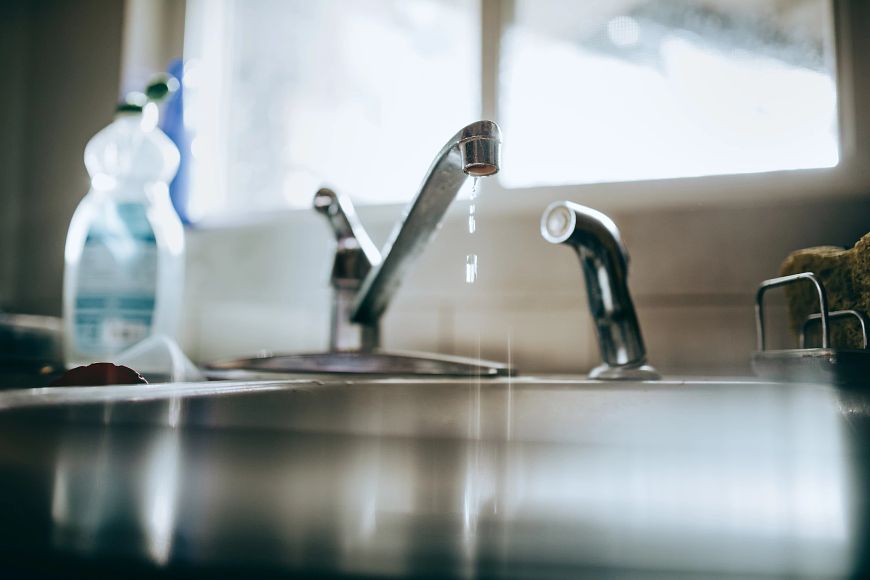 Water drips from a sink faucet.