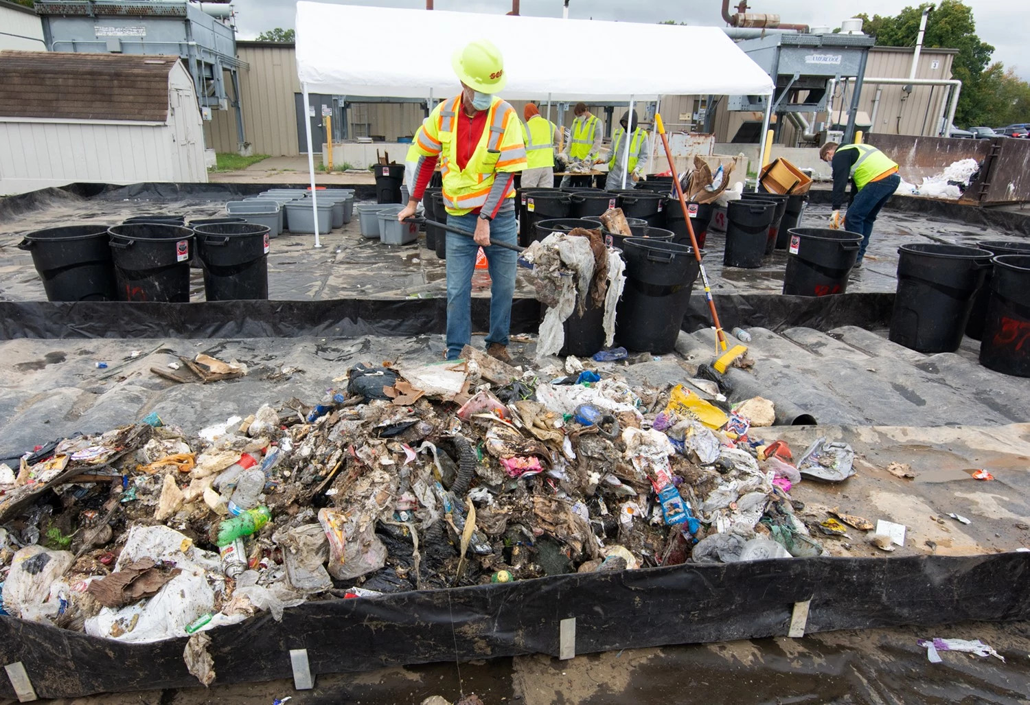 a worker scoops trash with a shovel at a landfill