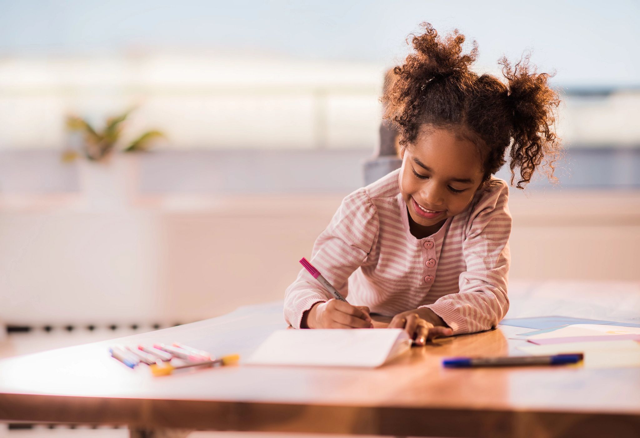 An image of a young girl drawing in a notebook.