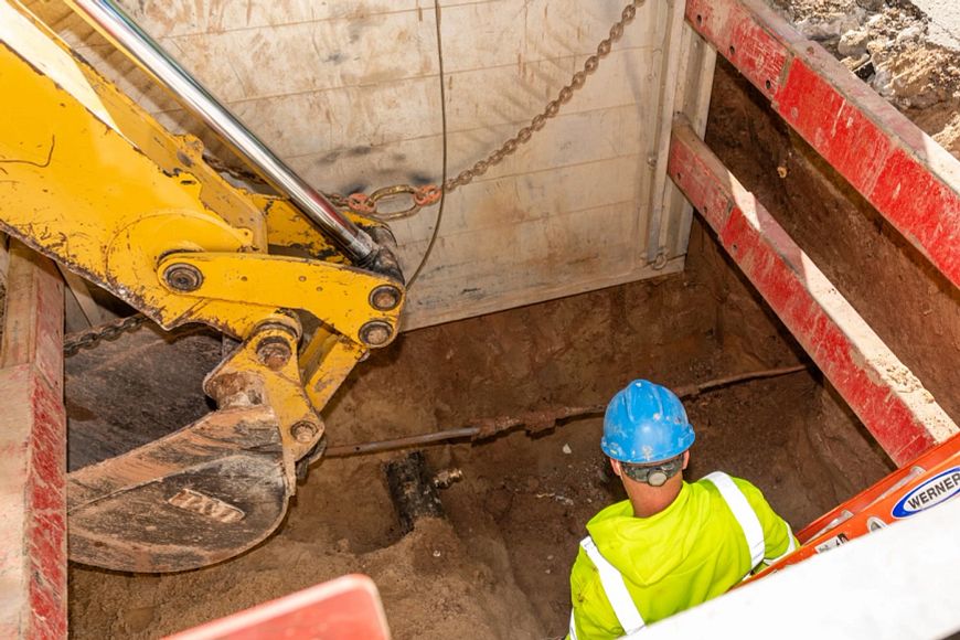 utility worker in a hole where lead service line is being removed