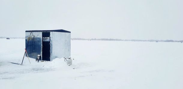An ice shanty on a frozen, snow-covered lake.