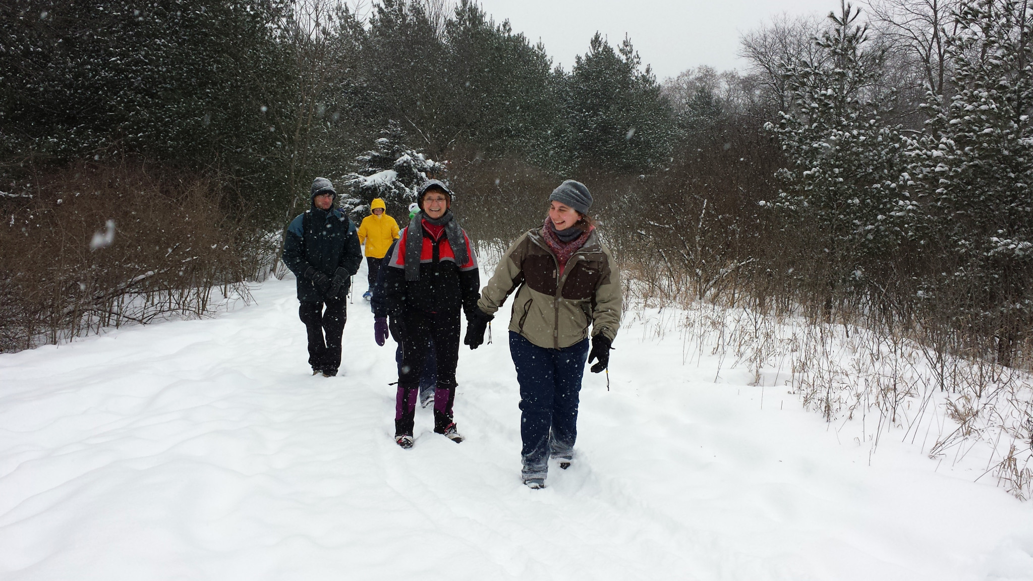 A group of women hike through the snow laughing.