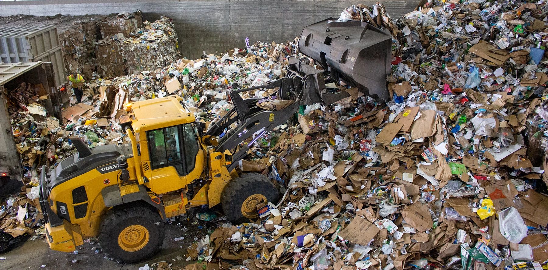 Heavy equipment scoops up a pile of recyclables in a recycling center