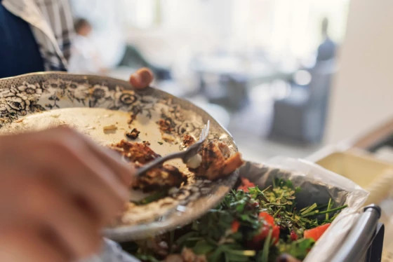 A person scrapes food scraps into a compost bin. 