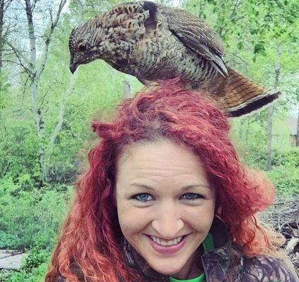 woman with ruffed grouse on her head