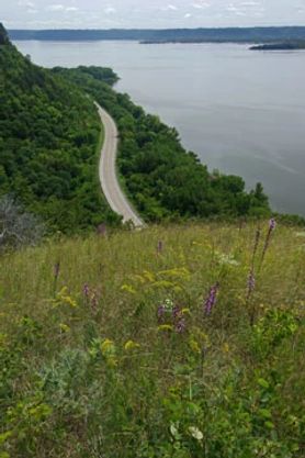 View of the landscape and road from on top of a grassy bluff.