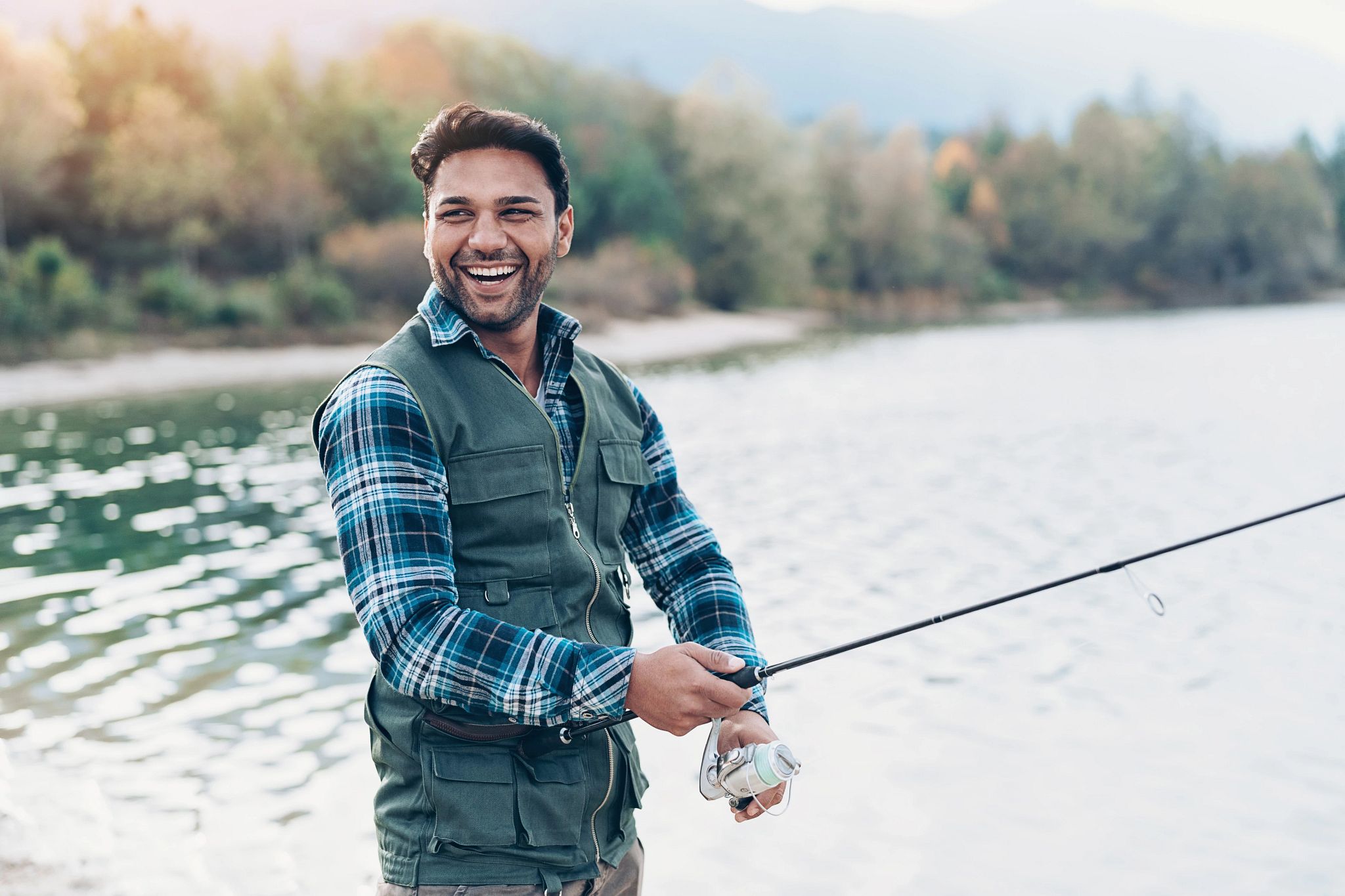 An image of a fisherman smiling while casting his reel. 