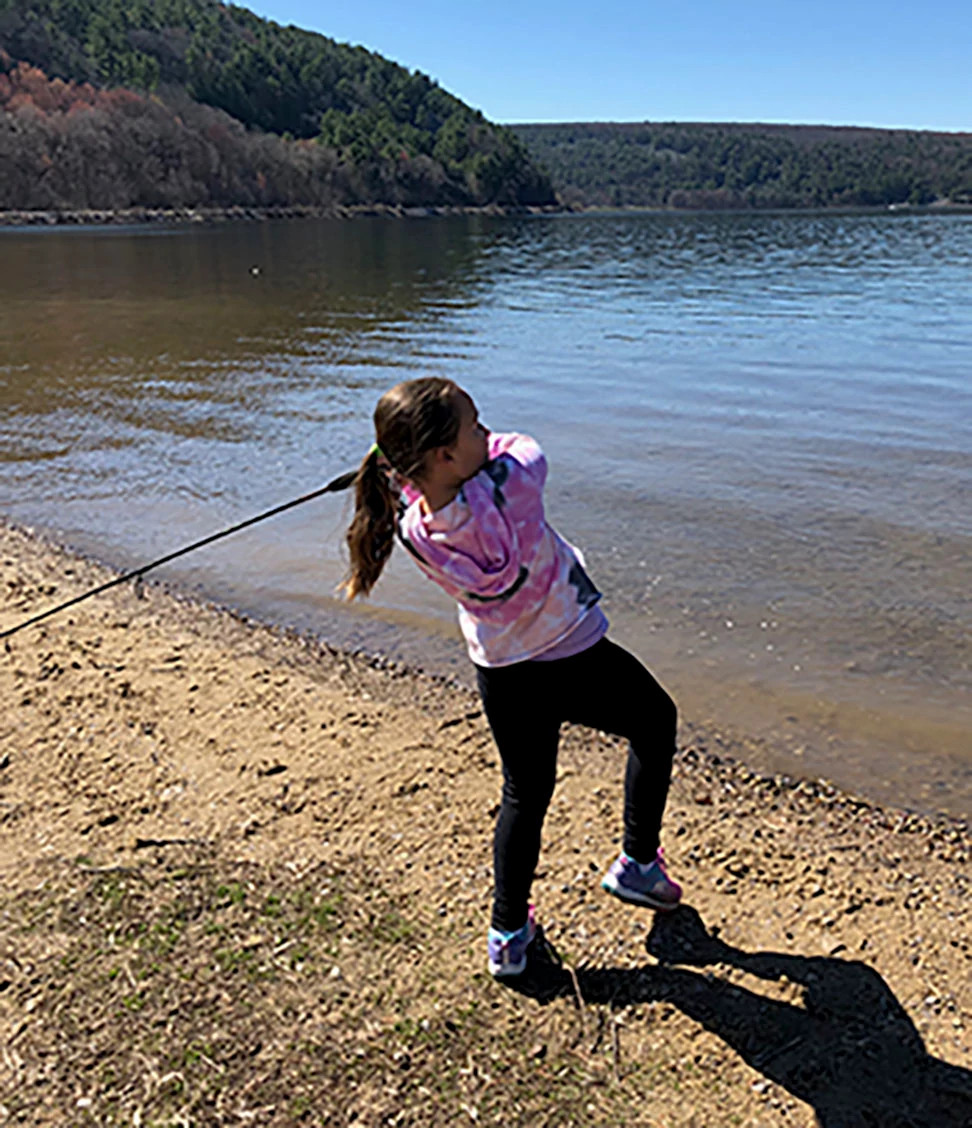 Girl swings fishing pole into lake