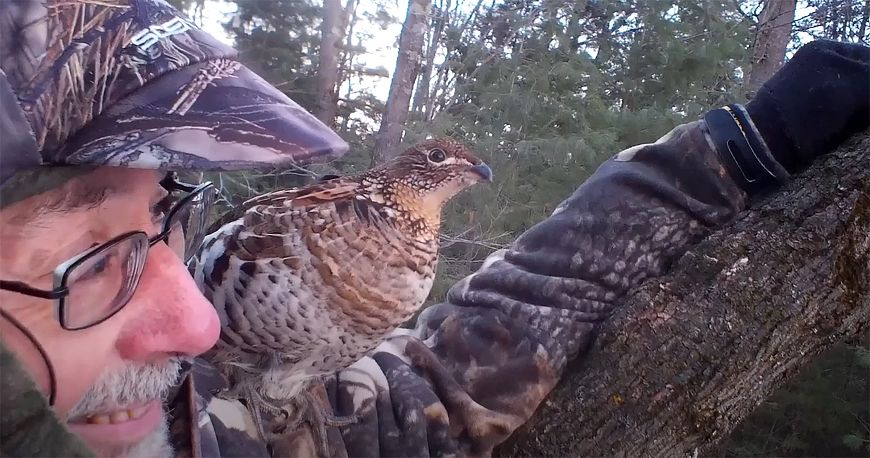 hunter in tree stand with ruffed grouse on his shoulder