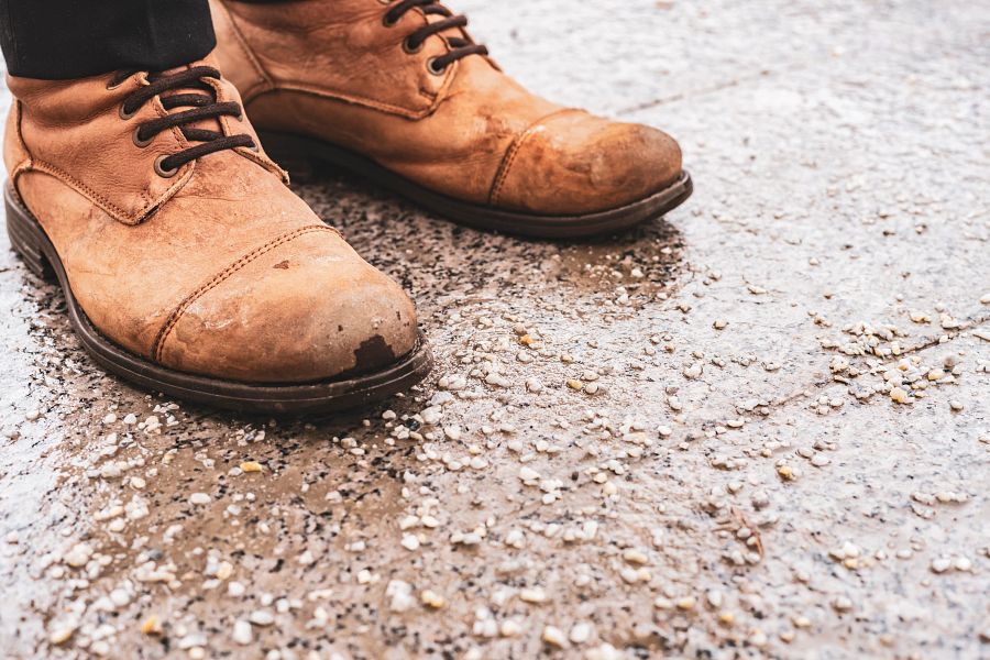 Damaged shoes on salted pavement in the city during winter season.