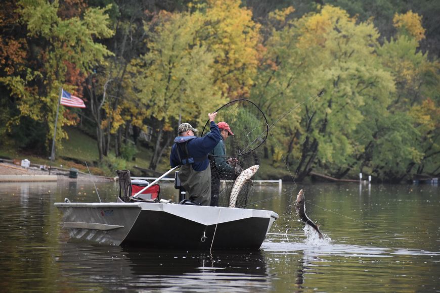 two people in a boat catching sturgeon with a hook and line