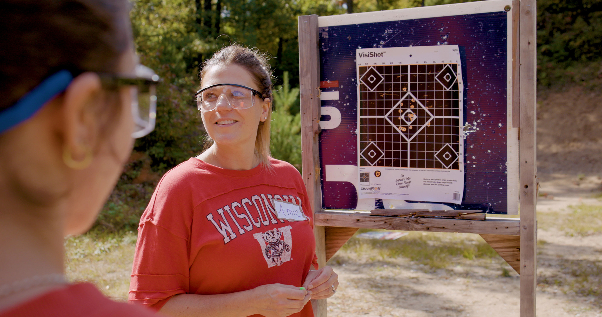 a woman wearing safety gear standing at a shooting range with another woman