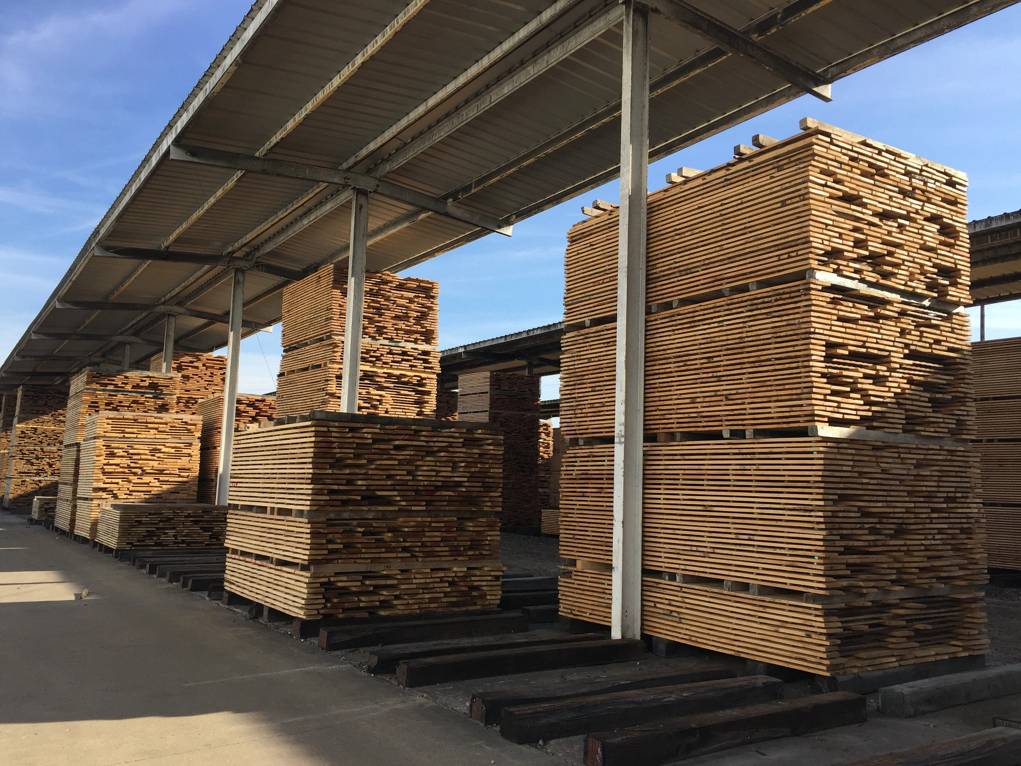 lumber stacked under a covered storage area
