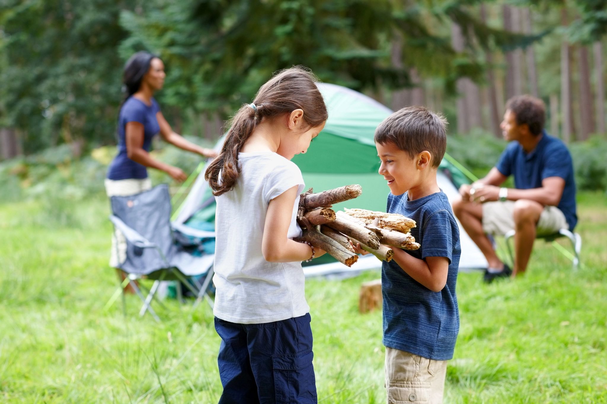 An image of a child handing firewood to another child. 