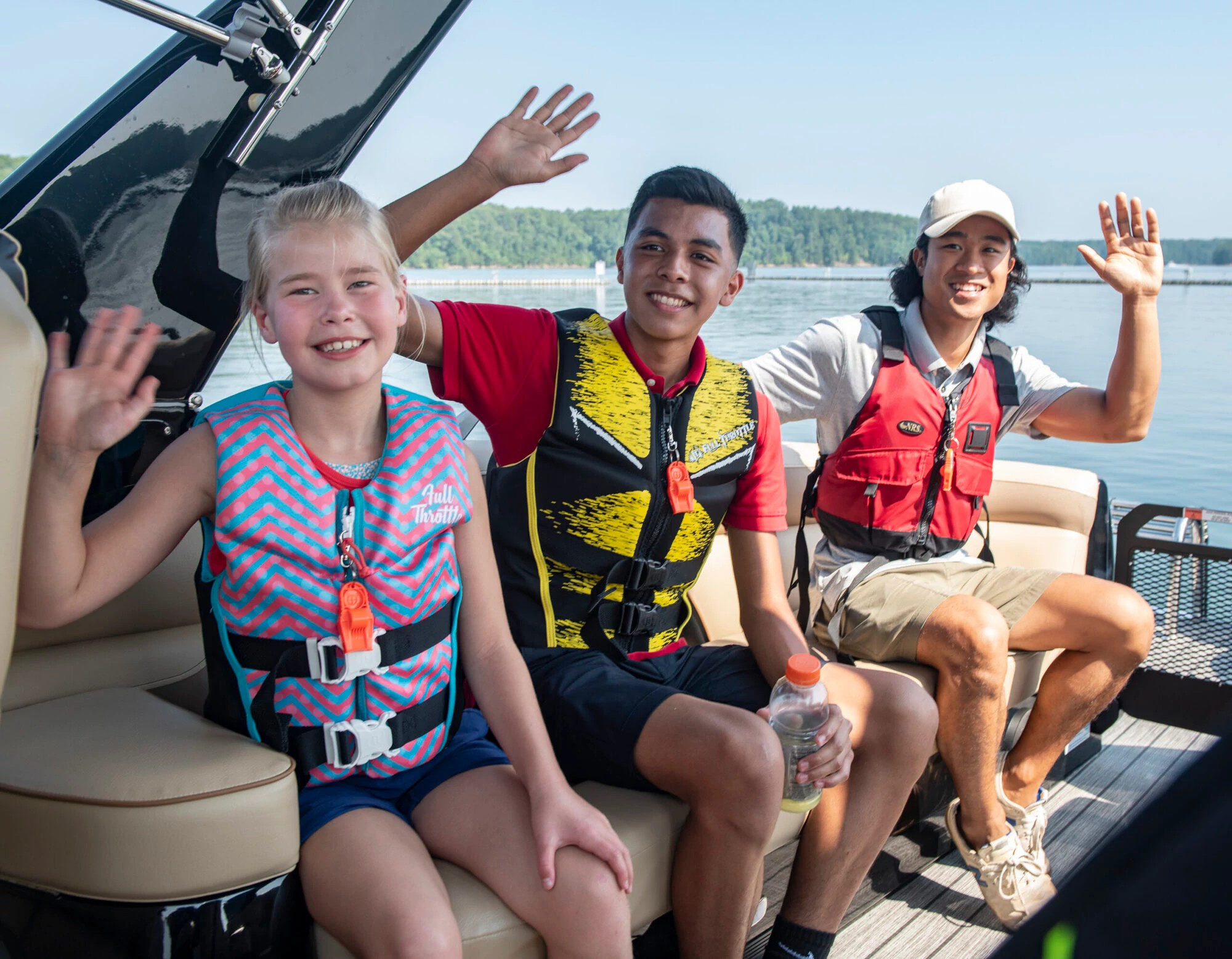 an adult man and two children wearing life jackets smile aboard a boat