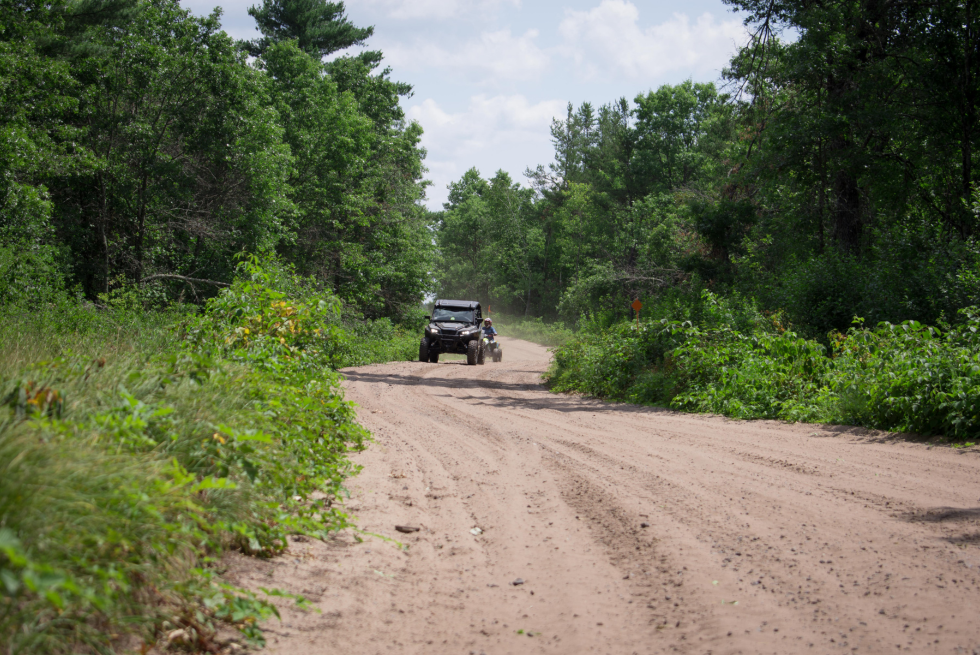 An ATV rides towards the camera on a trail in summer. 
