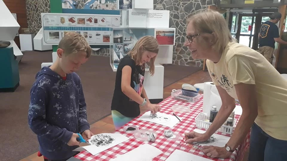 kids draw during an activity with a volunteer smiling leading the activity.