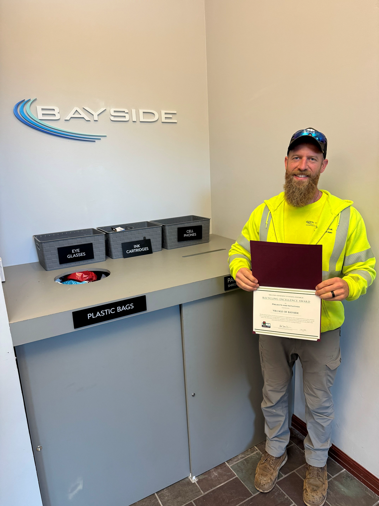 Shane Albers, Director of Public Works, holding the Recycling Excellence Award in front of the village’s recycling center