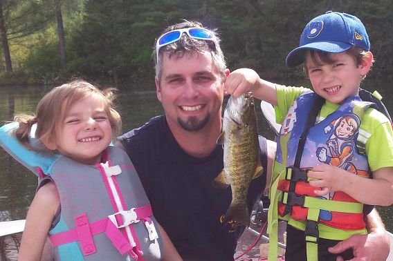 man and his two children holding caught fish