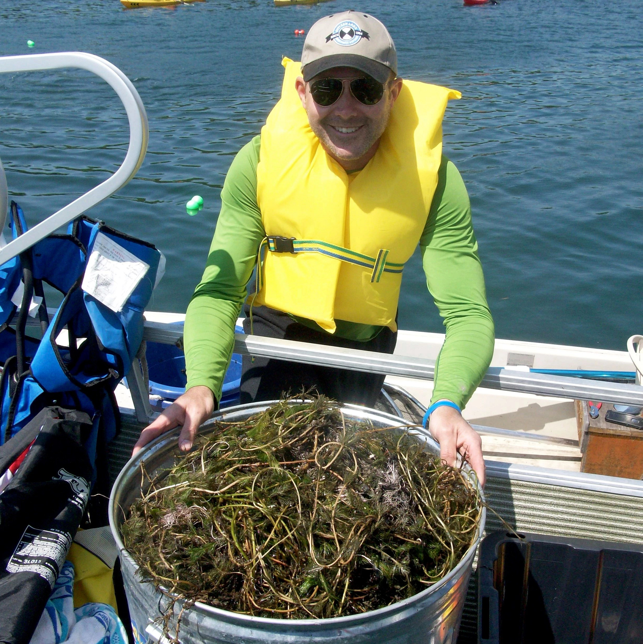 An invader crusader holds a tub of invasive species. 